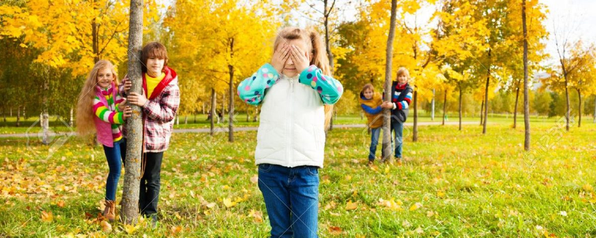 Children playing hide and seek in a park in the fall.