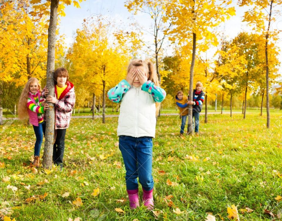 Children playing hide and seek in a park in the fall.